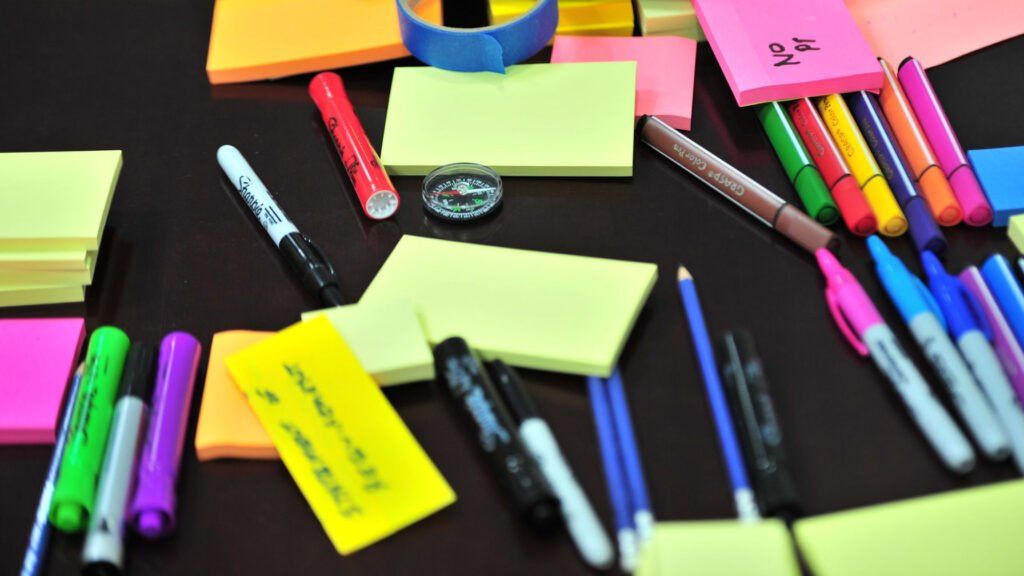 Sticky notes and pens with a discount code for the Planethoster WordPress plugin on a table.